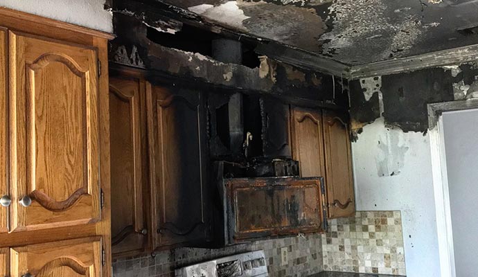 Fire damaged kitchen, charred cabinets and burned ceiling